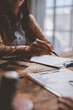 © crizzystudio - Professional businesswoman in an office setting, reviewing legal documents with a pen in hand. A scale of justice is visible, suggesting a legal or consulting environment