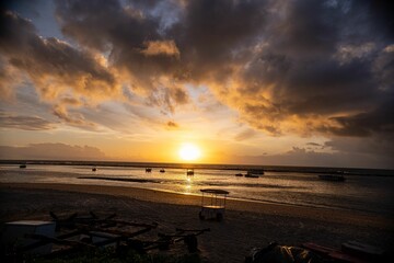 Wall Mural - sunset over a tranquil beach with silhouetted boats.