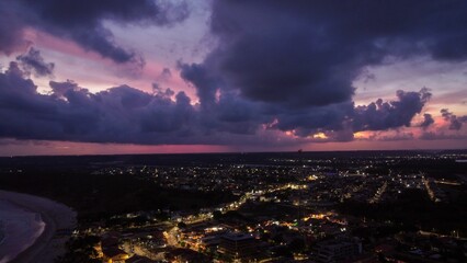 Wall Mural - aerial view of coastal city at dusk with dramatic clouds.
