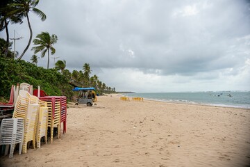 Wall Mural - Deserted tropical beach with stacked chairs and palm trees.