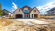 © wpw - Under construction luxury home with stone facade under clear blue sky.