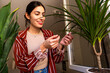 © we.bond.creations - The young woman analyses the health of her plants, smiling gently as she notices the growth and vitality of her greenery