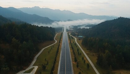 Wall Mural - Aerial view of road cutting through mountains with mist, for transport, travel