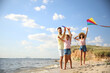 © New Africa - Happy parents and their child playing with kites on beach near sea. Spending time in nature
