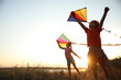 © New Africa - Cute little children playing with kites outdoors at sunset. Spending time in nature