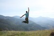 © New Africa - Sporty man jumping on grassy hill in mountains