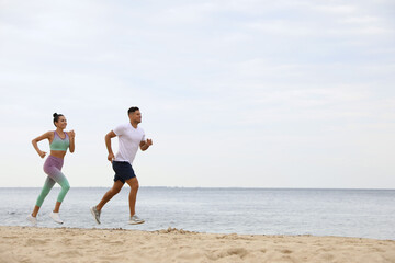 Wall Mural - Couple running together on beach, space for text. Body training