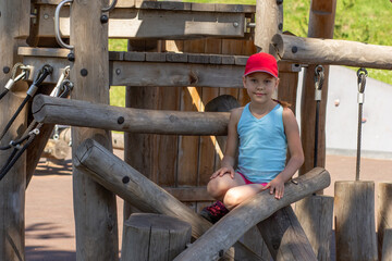 Happy and smiling caucasian child 7 8 years sitting on wood playscape