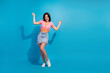 © deagreez - Cheerful young woman in trendy pink top posing on blue background, exuding youthful energy and charm