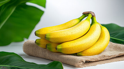 Wall Mural - Fresh bananas with speckled skin on linen cloth surrounded by green leaves