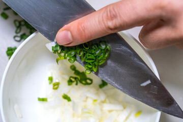 Wall Mural - moving the slices of green onion into the bowl with a knife