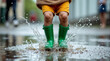 © alex - Child jumping in rain puddle, wearing green rubber boots, playful energy, muted urban background