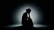 © Tanakrit - A silhouette of a person sitting in a contemplative pose, surrounded by soft light, evoking feelings of introspection and solitude.