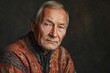 © ChaoticMind - Elderly man wearing traditional colorful attire poses with a thoughtful expression in a dimly lit environment