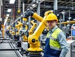 © Teepanun - A male technician in a factory wearing a uniform and safety goggles, using a control panel to operate a robotic arm, manufacturing, assembly line, robotic arm