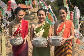 Portrait smiling  young pretty Thai women in colorful  traditional Thai costumes holding silverware bowl celebrating Songkran festival in Chiangmai, Thailand