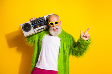 Canvas Print - Charismatic elderly man in vibrant attire holding a retro boombox against a bright yellow backdrop showcasing energy and personality