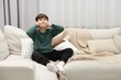 © New Africa - Annoyed boy covering his ears due to loud sound on sofa at home, space for text
