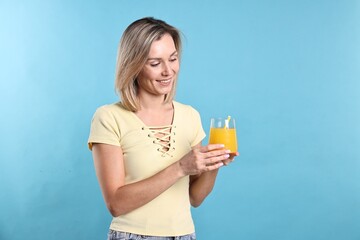 Wall Mural - Woman with glass of orange juice on light blue background. Refreshing drink