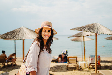 Young caucasian woman is going to the beach with straw bag	