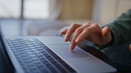 Wall Mural - Closeup person typing laptop remotely. Man hands using touchpad in light office
