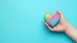 © Valentina - Child Holding a Colorful Heart on Blue Background