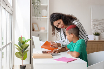 Wall Mural - Little African-American boy with his mother doing lessons at home