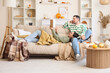 © Pixel-Shot - Happy young couple reading book together at home on autumn day