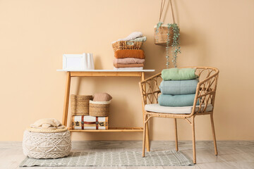 Wall Mural - Chair and table with stacks of clean clothes near beige wall