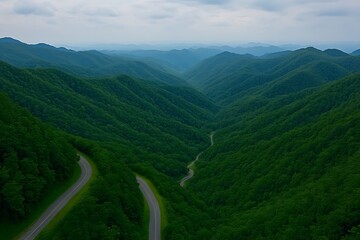 Poster - Road winds through lush green mountain valley, under a hazy sky. Background for travel blog