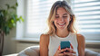 © Sync - Happy young woman using smartphone at Home, smile and hold phone on her hand with internet technology use of shopping, search, chat, message at inddor living room with beautiful natural light