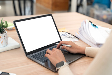 Wall Mural - Close-up image of a woman working on laptop computer at a table, typing on the laptop keyboard. the laptop with a white screen mocku