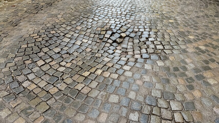 A cobblestone street with visible unevenness highlights urban infrastructure challenges and is ideal for illustrating road maintenance issues