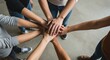 © Alper AI - Aerial photograph of a group of six people with their hands interlocked in the center, creating a sense of unity and cooperation, against a plain, light-colored concrete floor background.