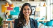 © Rhony - Young smart indian businesswoman, smiling face, standing in blur background of creative colorful office interior design.