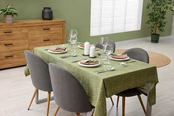 Aufkleber - Stylish table setting with olive tablecloth, glasses and candles in dining room