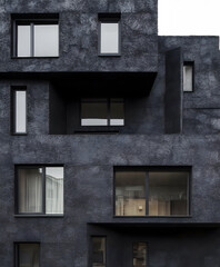 Fototapete - A modern, dark-hued building with various window styles, showcasing a minimalist and textured exterior design