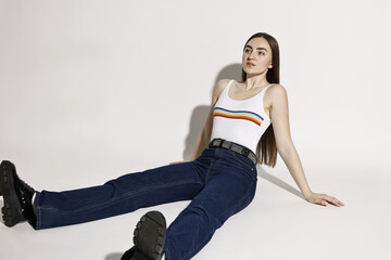 Poster - Beautiful young woman in stylish jeans posing on light background