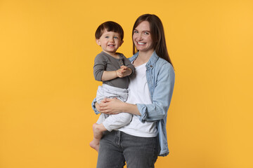 Wall Mural - Happy mother with her cute little son on yellow background