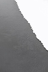 Wall Mural - diagonal section of flat white snow at edge of dark river water