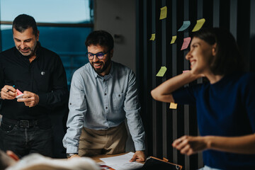 Poster - Multigenerational colleagues gather in a creative business meeting, sharing ideas and strategies. The team is engaged in a collaboration using colorful sticky notes, showcasing teamwork and innovation