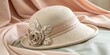 © Thanawat_Suesoypan - Elegant Vintage Hat with Floral Decoration Resting on Soft Fabric Background in Neutral Tones