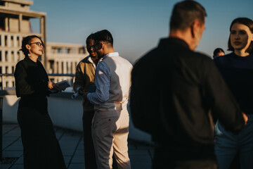 Sticker - A group of multiracial colleagues engage in a brainstorming session on a high-rise balcony during sunset, showcasing diversity and collaboration in a modern business setting.