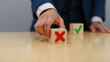 © FreemiumStock - Hand pointing at decision-making blocks with red X and green checkmark symbolizing choice, risk, and strategic business decisions