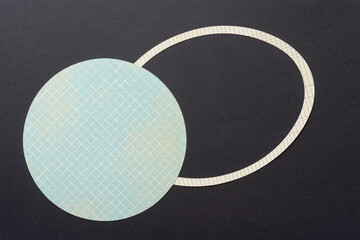 blue paper circle with pattern and oval ring shape on black paper