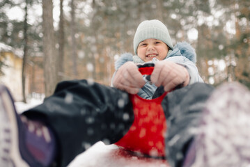 Smiling girl sledding down snowy hill in winter forest