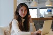 © Irina Fedurtso - A woman wearing a white sweater is intently using a laptop now