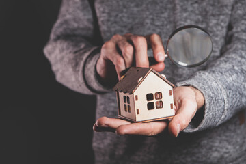 a man 's hand holding a wooden toy house