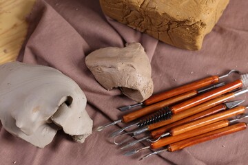 Wall Mural - Set of different crafting tools and pieces of clay on wooden table, top view