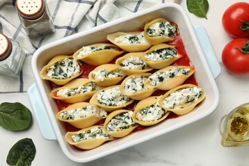 Sticker - Delicious conchiglie pasta with ricotta cheese, spinach and tomato sauce in baking dish on white marble table, flat lay